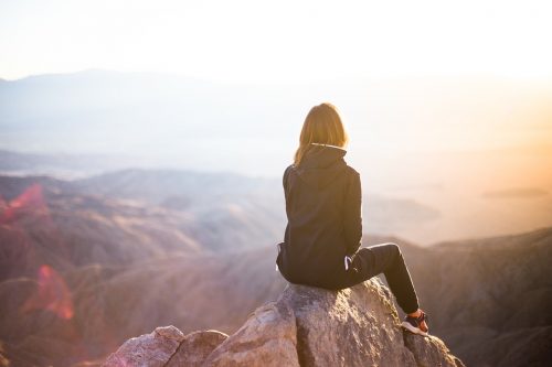 woman sitting on the rock on top of the mountain